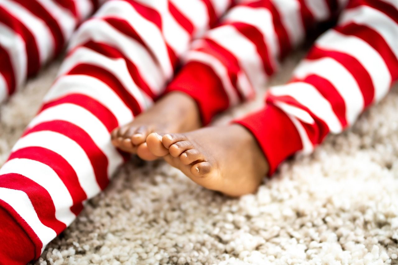 Children's feet in matching red-and-white striped Christmas pajama pants