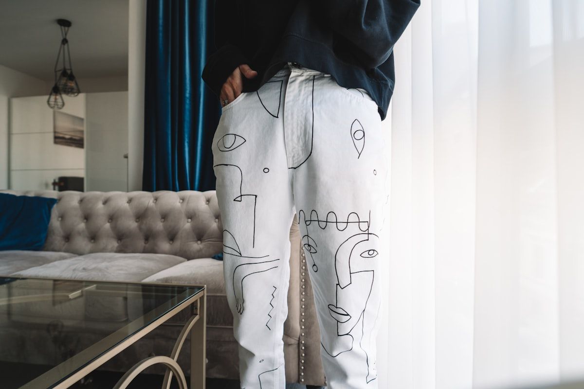 White lounge pants with an all-over line-drawing print worn full length beside a sofa