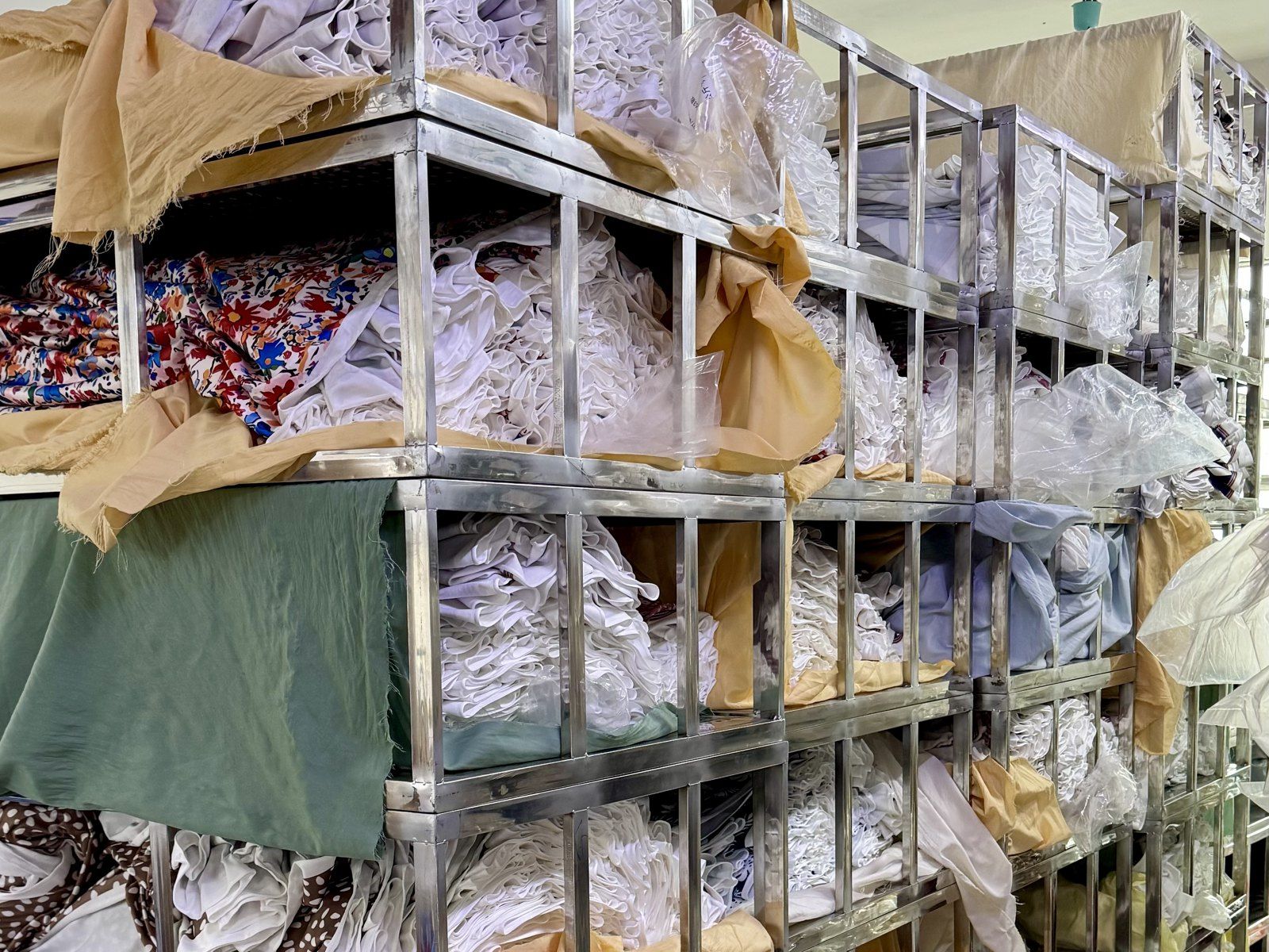 Steel racks of bundled fabric and cut pieces, covered with cloth, in our fabric store