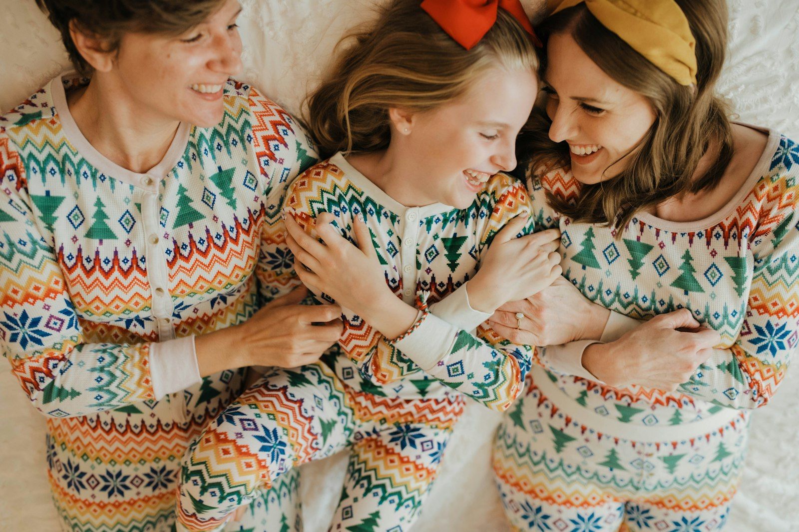 Two adults and a child wearing the same all-over Fair Isle pajama print in three different garment sizes