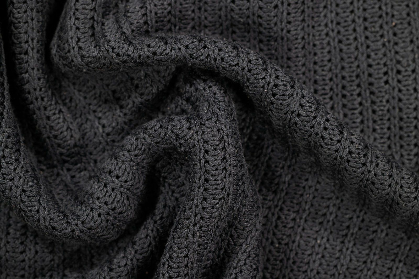 Close-up of a heavy grey knit fabric folded over itself, showing the stitch structure that decides weight and recovery