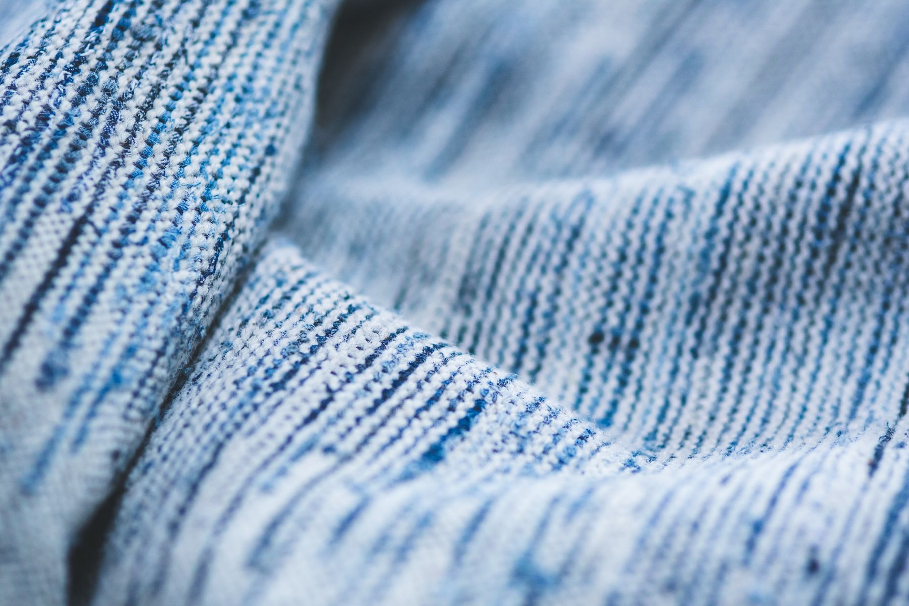 Close-up of a blue textured knit fabric showing the rib and surface of the weave