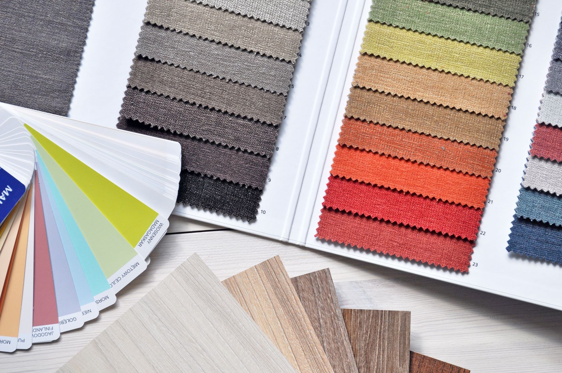 Fabric swatch cards and a colour fan laid out on a table for material selection