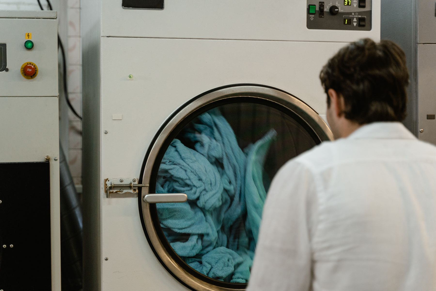 Person loading blue laundry into a large front-loading washing machine