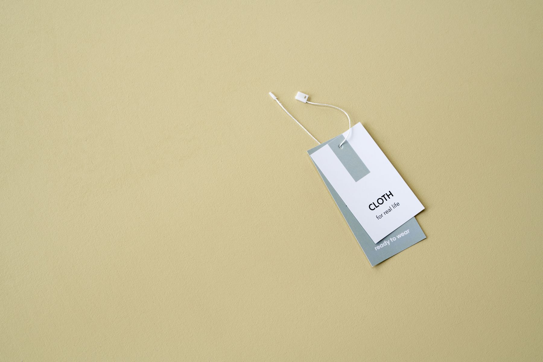Printed clothing hang tag with a string attachment lying on a plain cream background