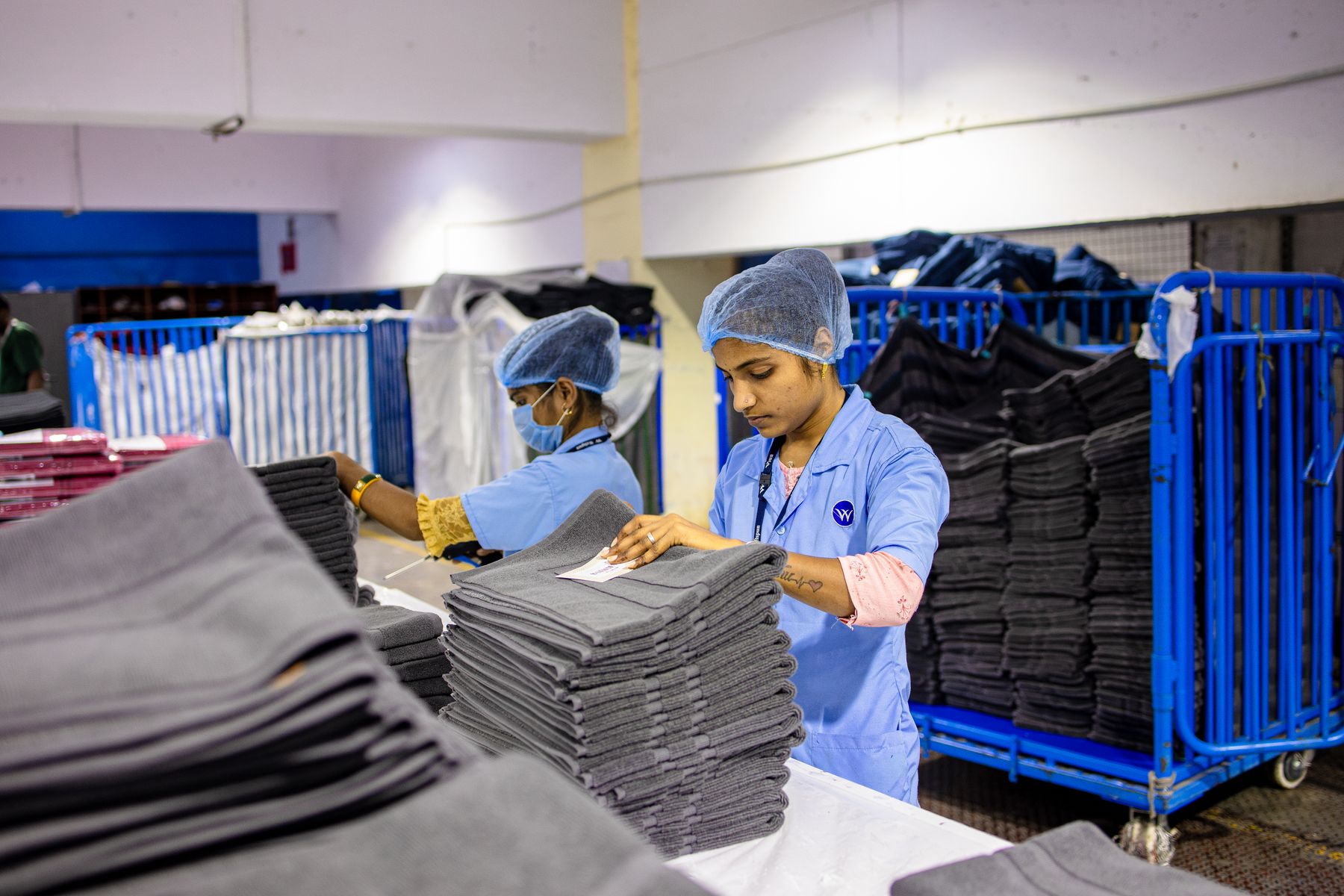Workers folding and stacking large quantities of finished garments