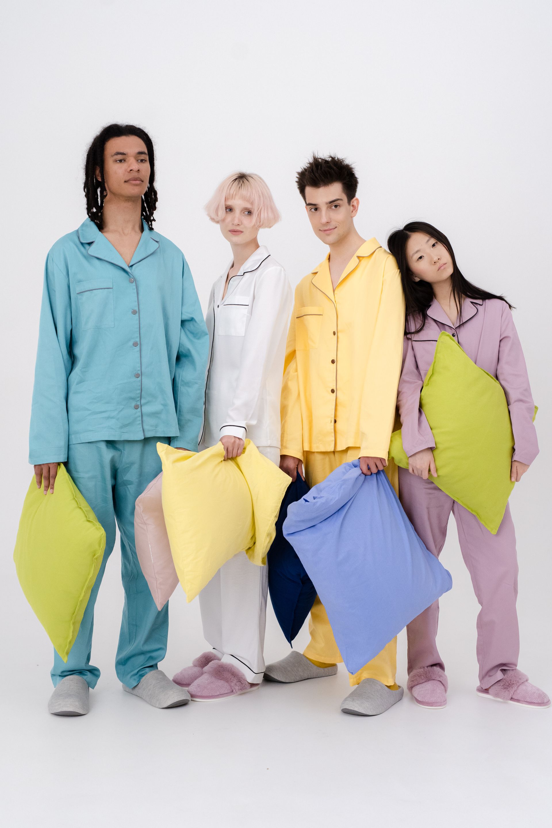 Four adults wearing colorful two-piece pajama sets in a white studio