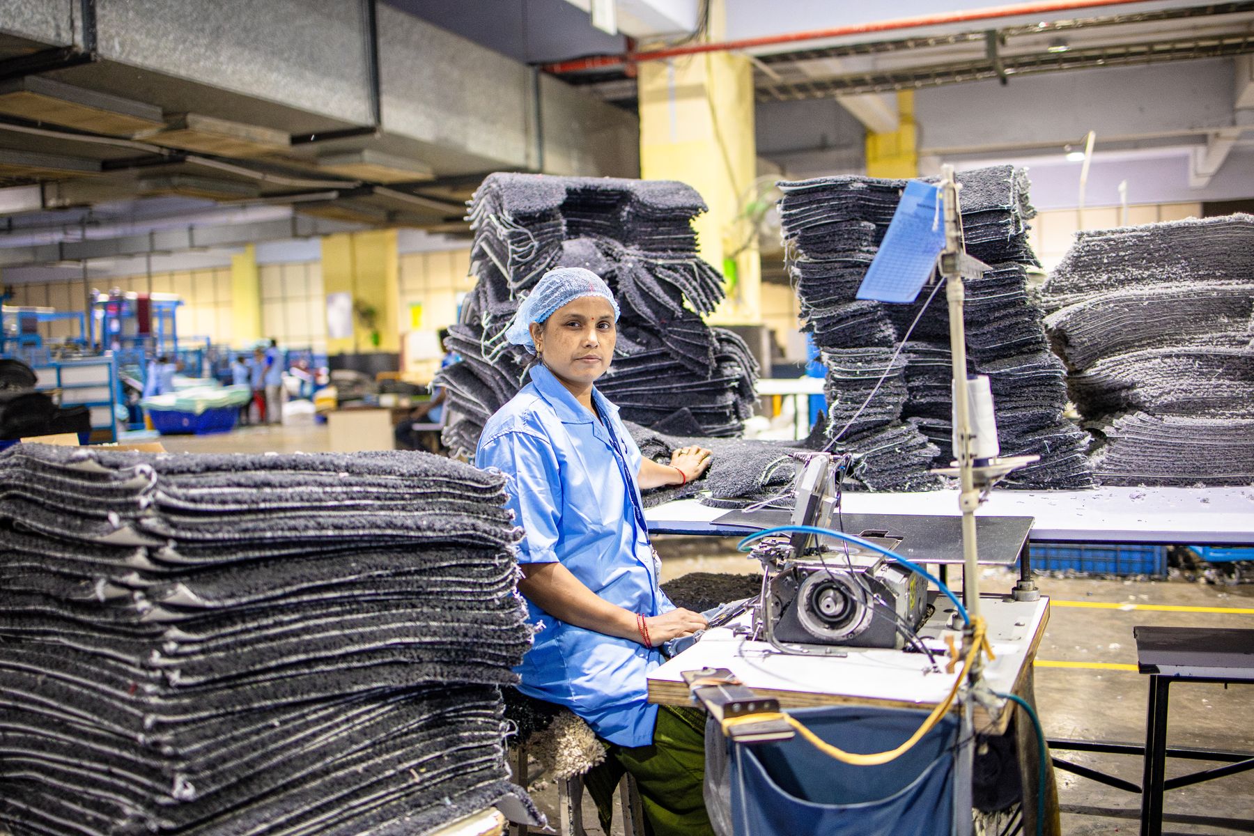 Factory worker beside tall stacks of folded finished garments