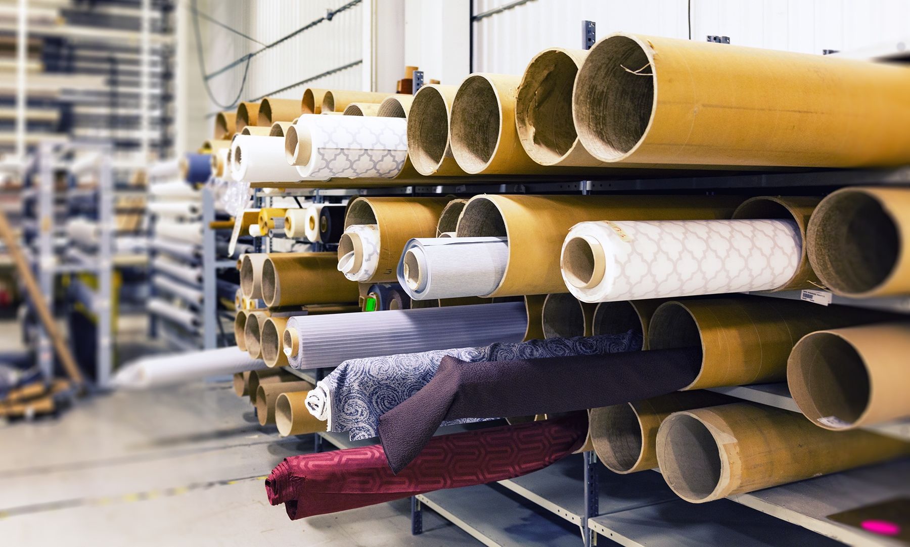 Rolls of fabric stacked on racks in a textile warehouse