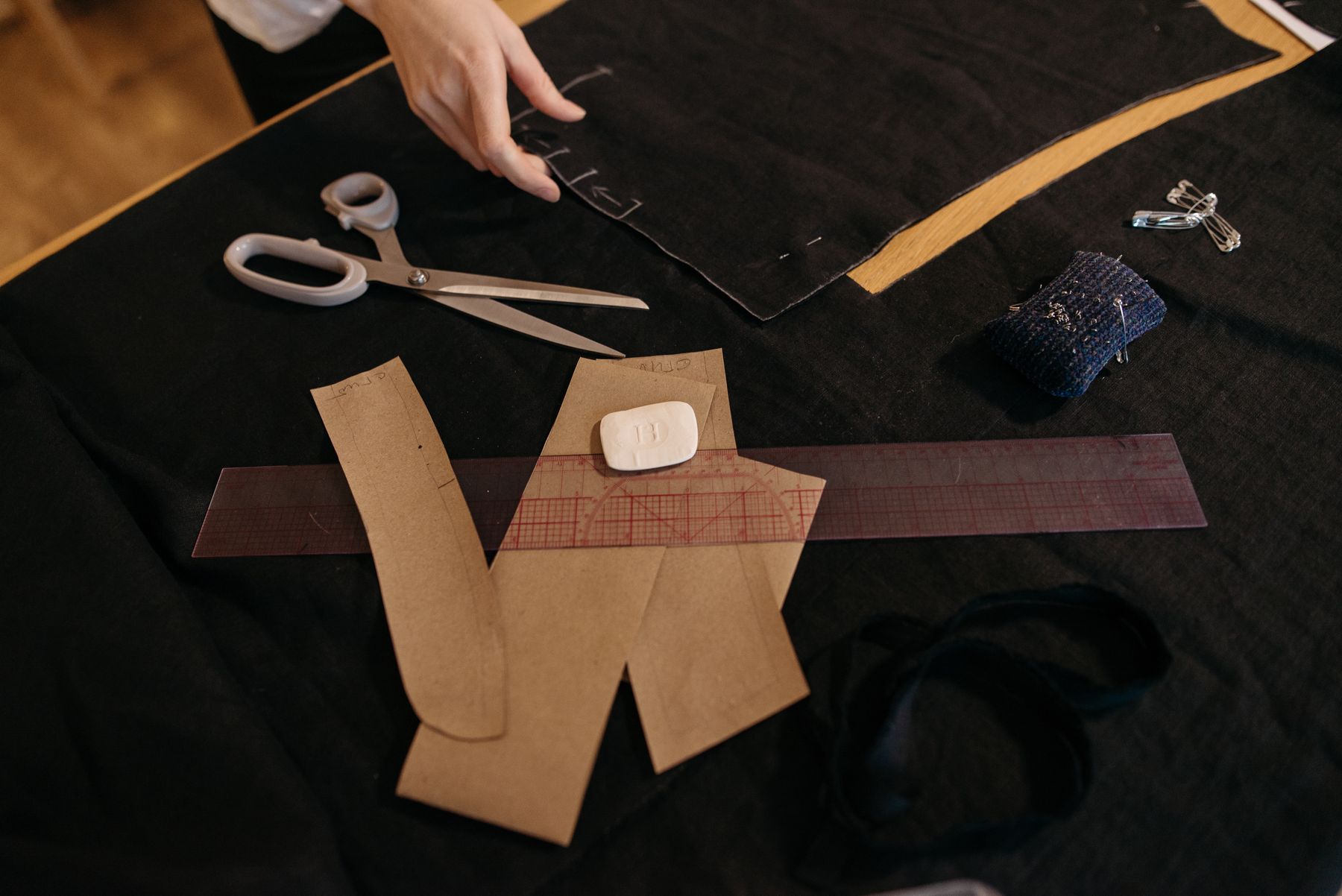 Paper pattern pieces, scissors and chalk laid out on dark fabric