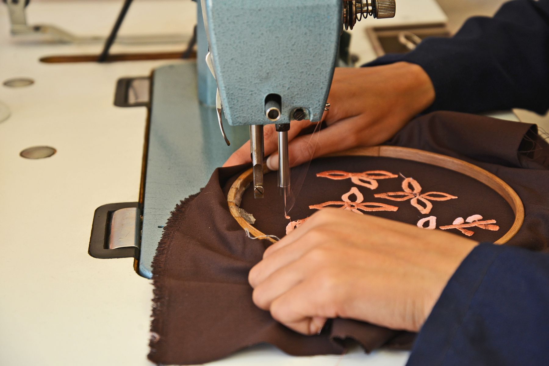 Embroidery machine stitching a floral motif inside a hoop