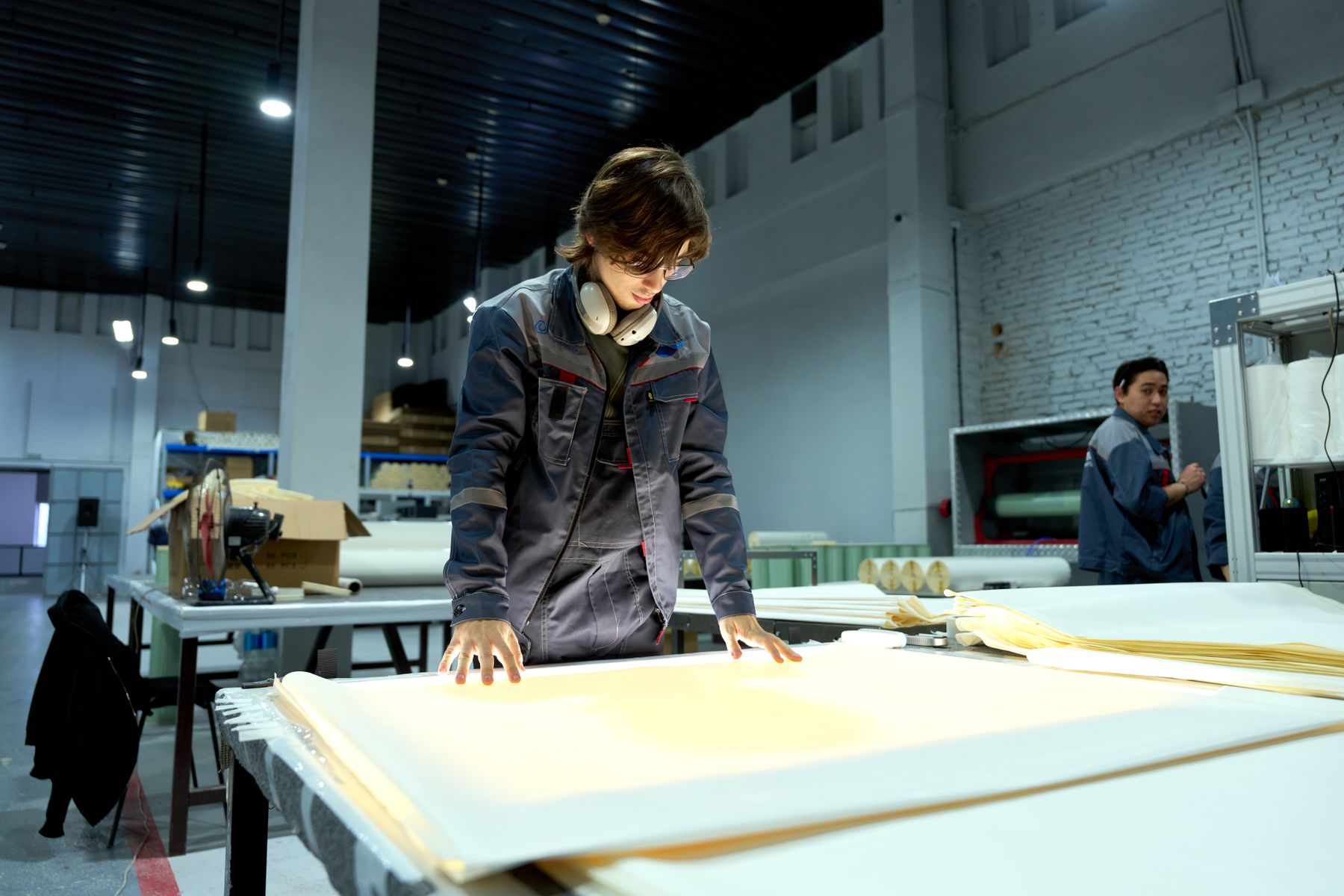 Worker examining a flat panel on an inspection table in a factory