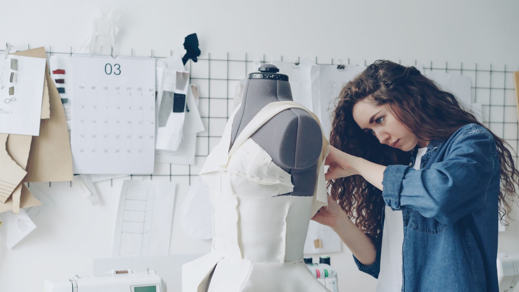 Designer working on a garment fitted to a dress form in a sample studio