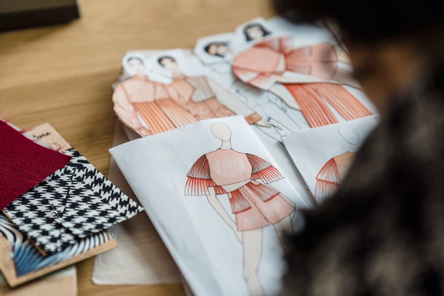 Fashion sketches laid out beside fabric swatches on a studio desk