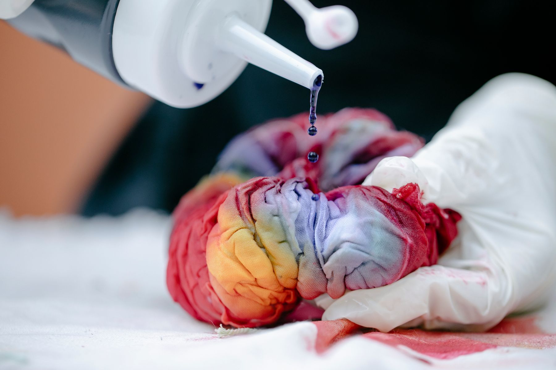 Gloved hand applying dye to fabric during colour testing