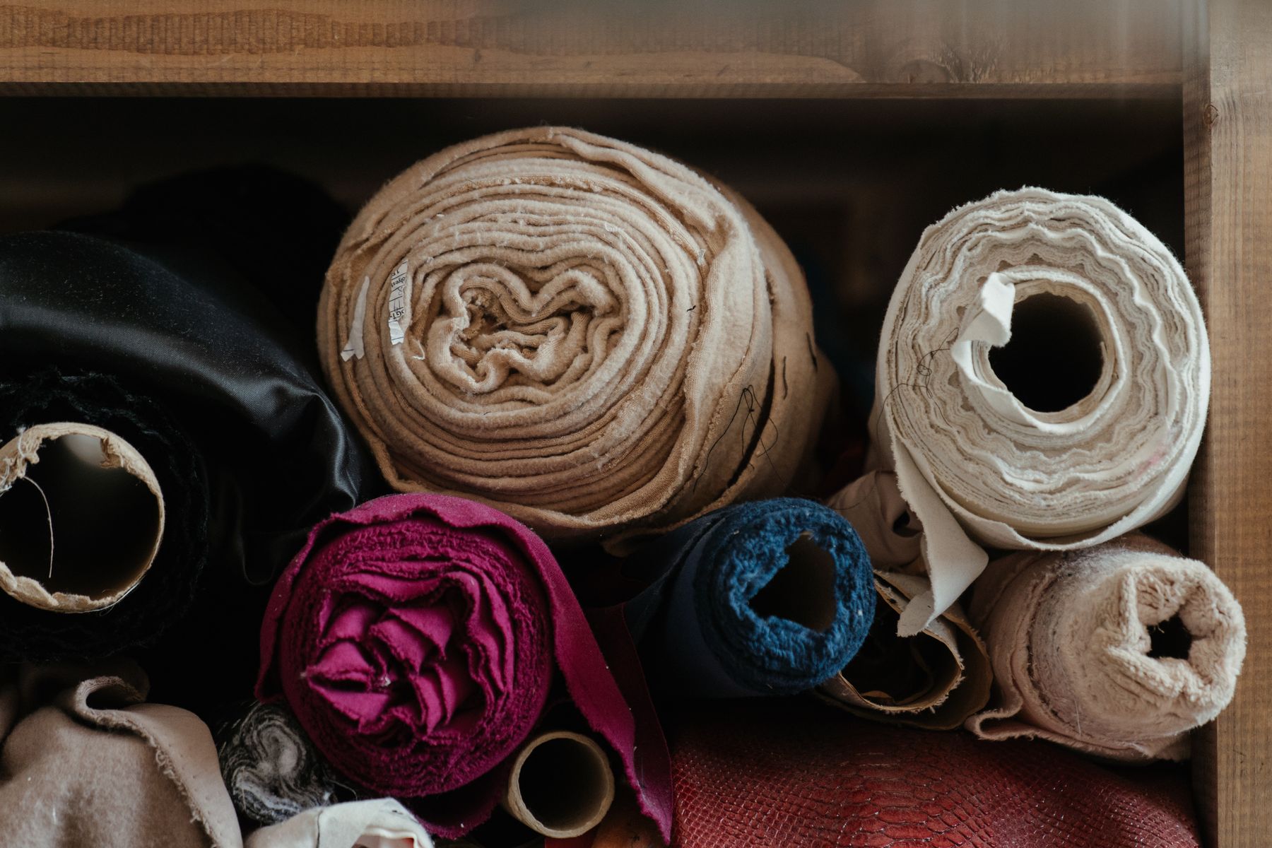 Rolled fabrics stored on end, showing different weights and colours