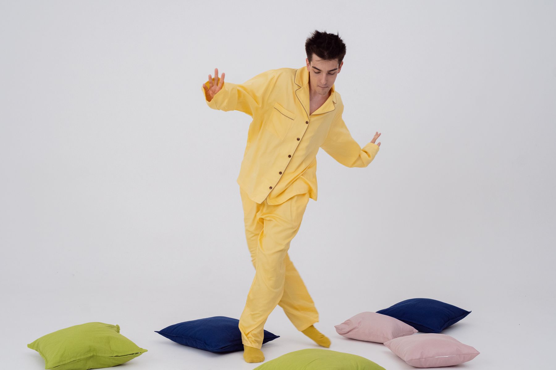 Man wearing a yellow button-front two-piece pajama set in a white studio