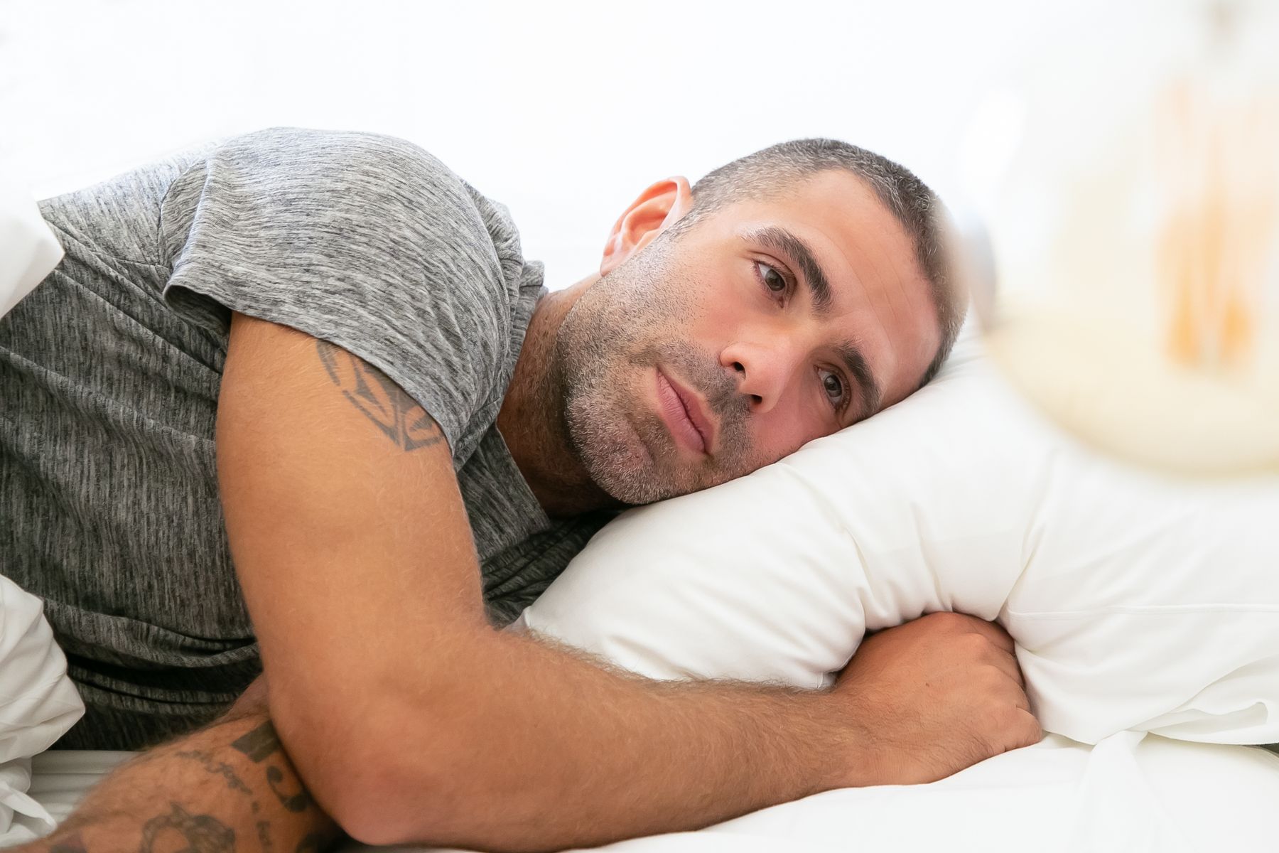 Man in a soft grey top resting against a pillow