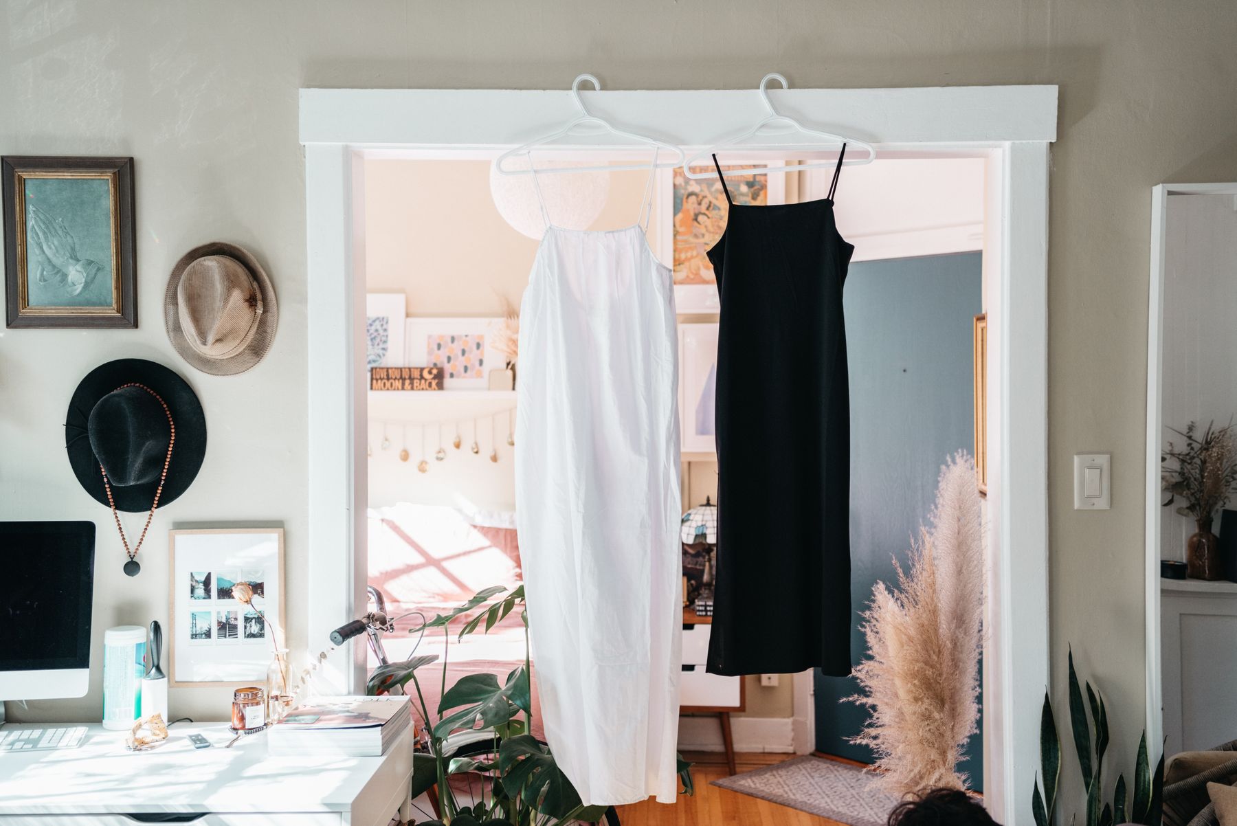 Long white and black gowns hanging on a rail in a doorway