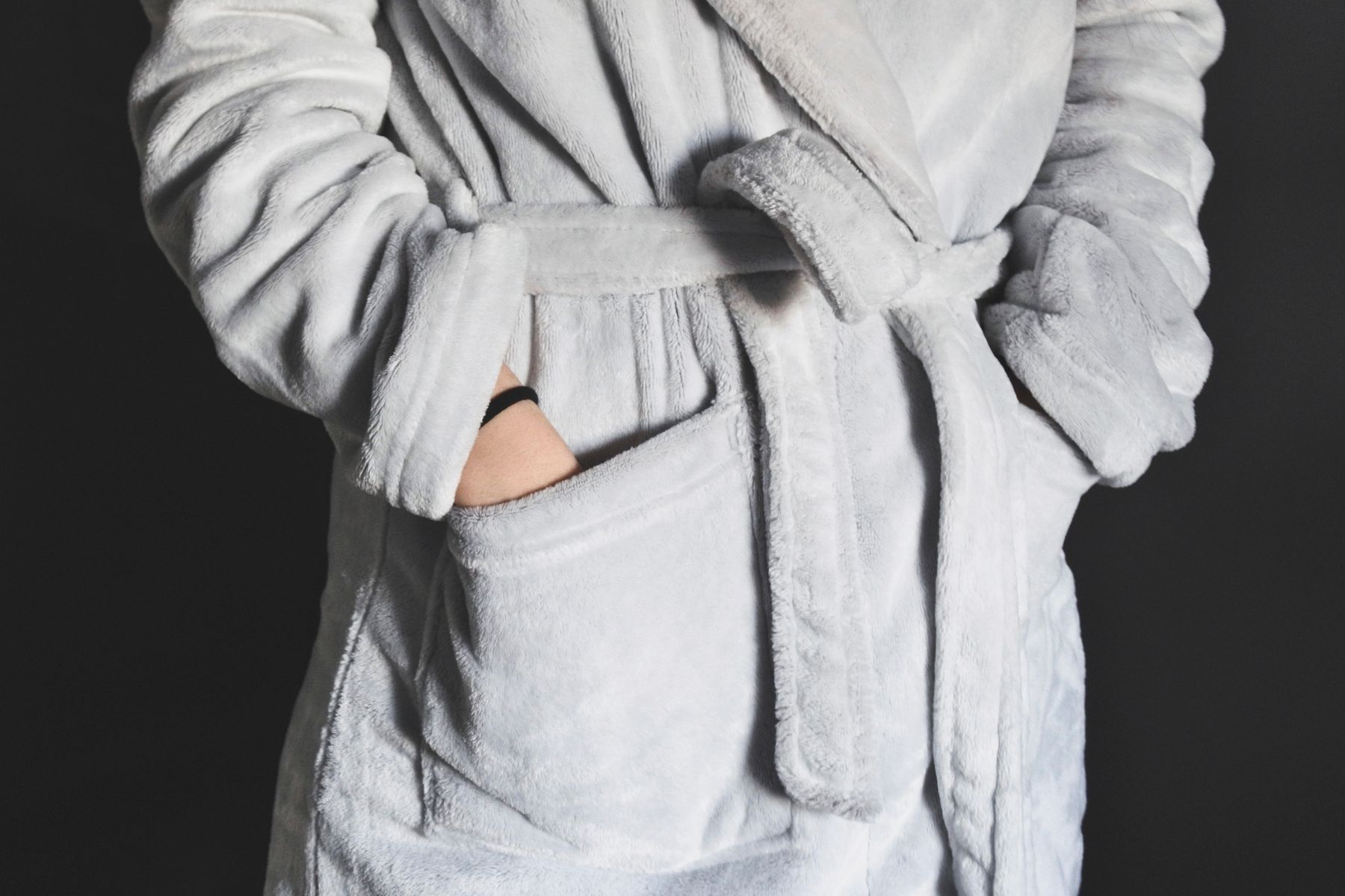 Grey fleece robe tied at the waist with hands in the pockets