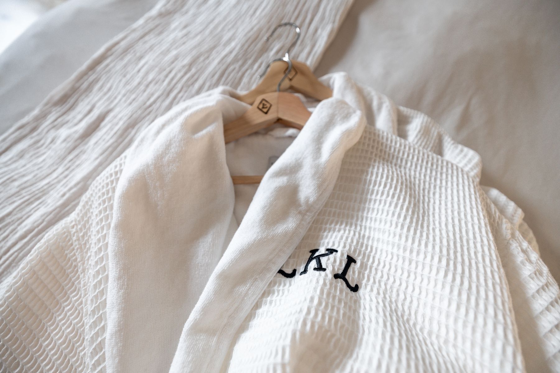 White waffle robe on a hanger with an embroidered monogram