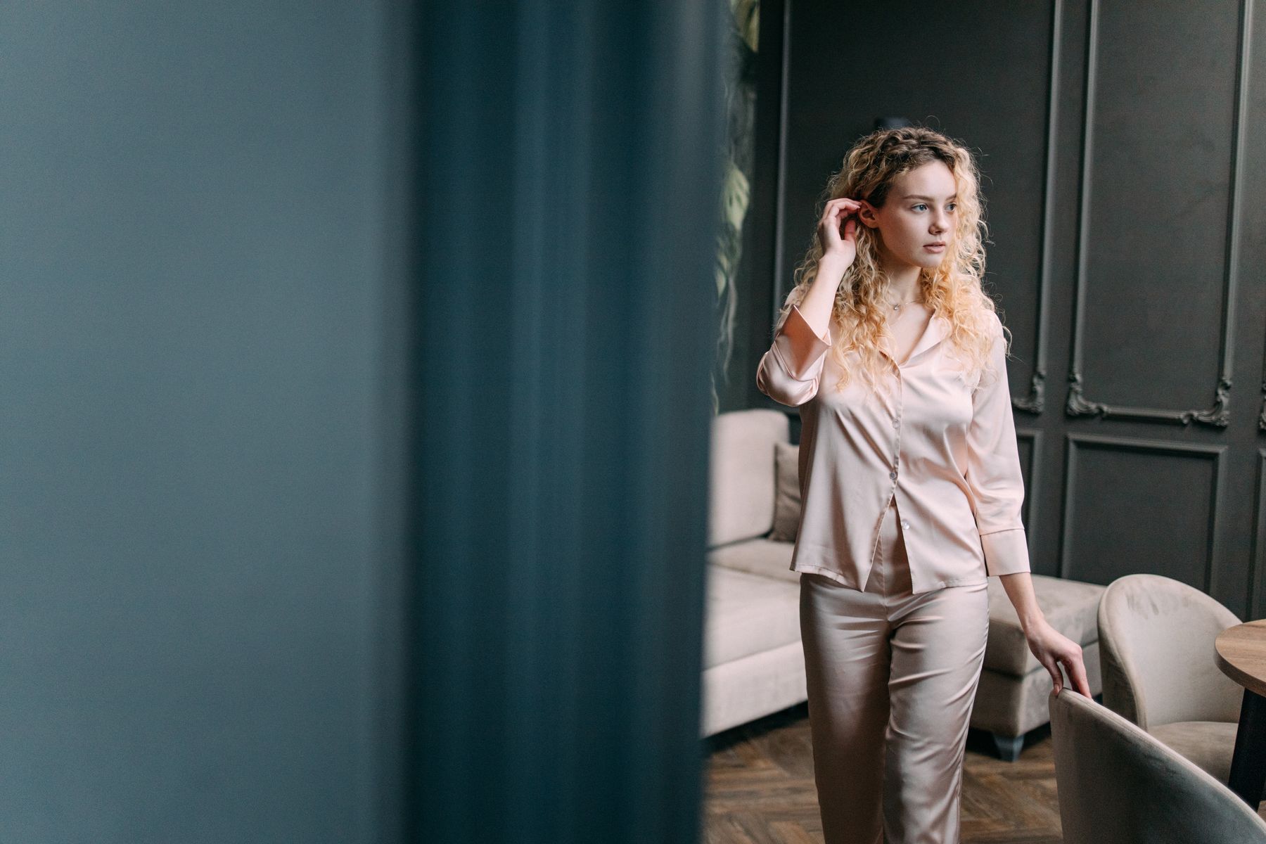 Woman wearing a satin pajama set beside a window